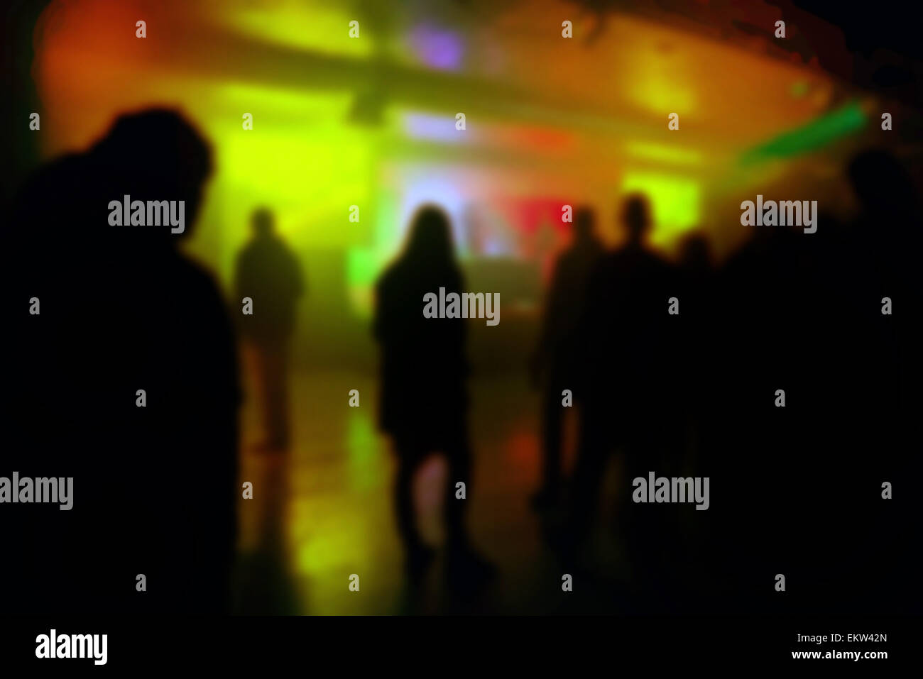 Blur Defocused Silhouettes of Young People on DJ Concert, Fans Watching electronic music DJ Performing on Stage. Stock Photo