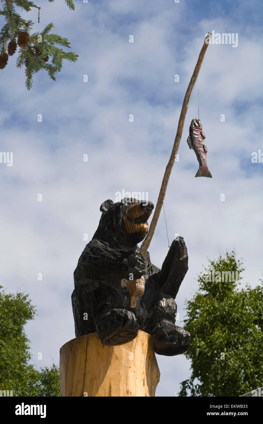 bear with a fishing pole Wood Carving Of A Bear Sitting On A Log With A Fishing Pole And Hooked Fish  Located In Downtown Talkeetna, Alaska Stock Photo