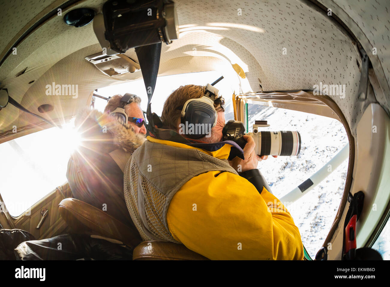 Official Iditarod photographer, Jeff Schultz, photographing from an airplane flying over Kaltag during the 2014 Iditarod, Alaska Stock Photo