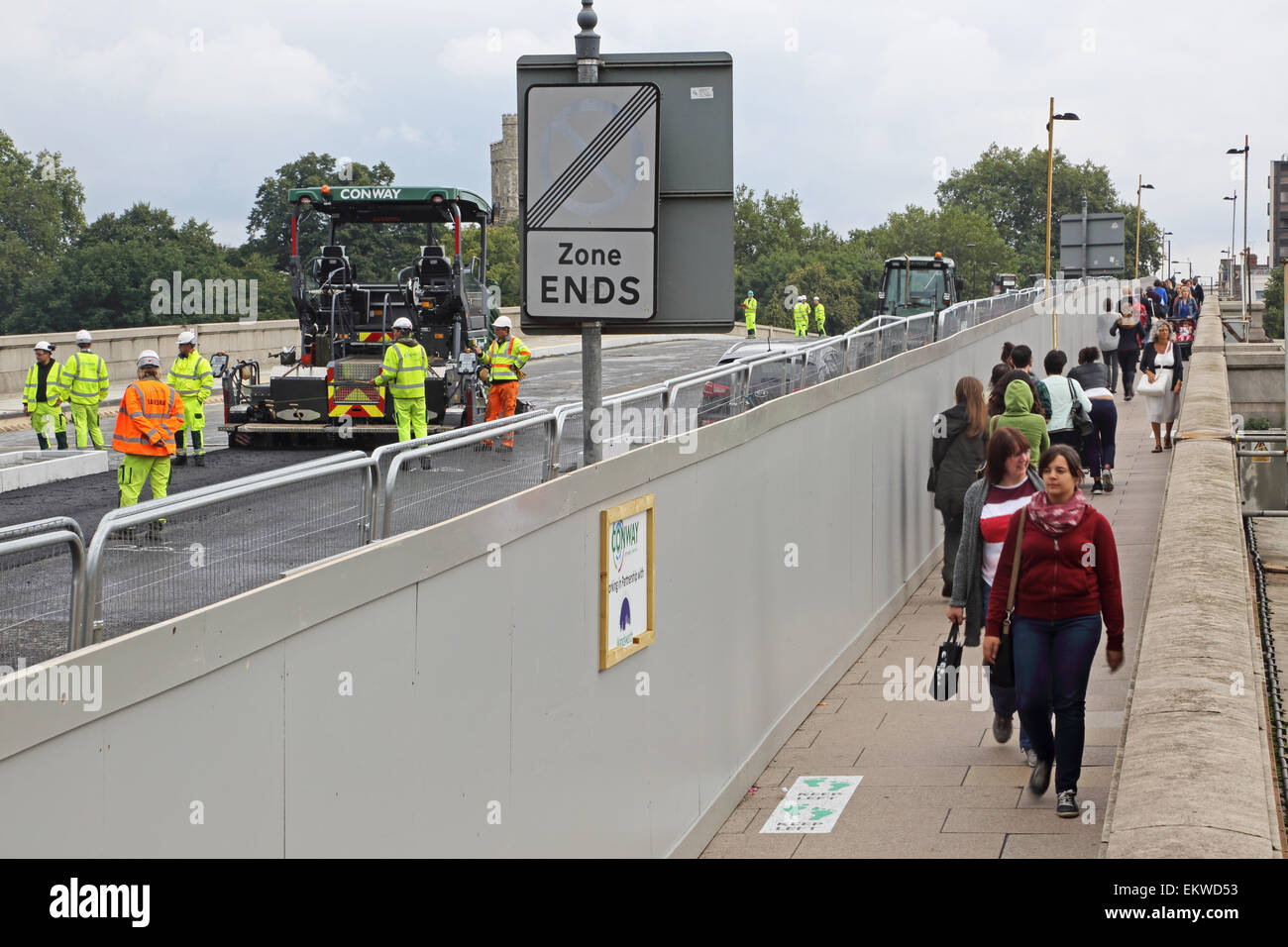 Pedestrians segregated from construction work by a temporary hoarding on Putney Bridge, west London. Bridge closed to traffic. Stock Photo