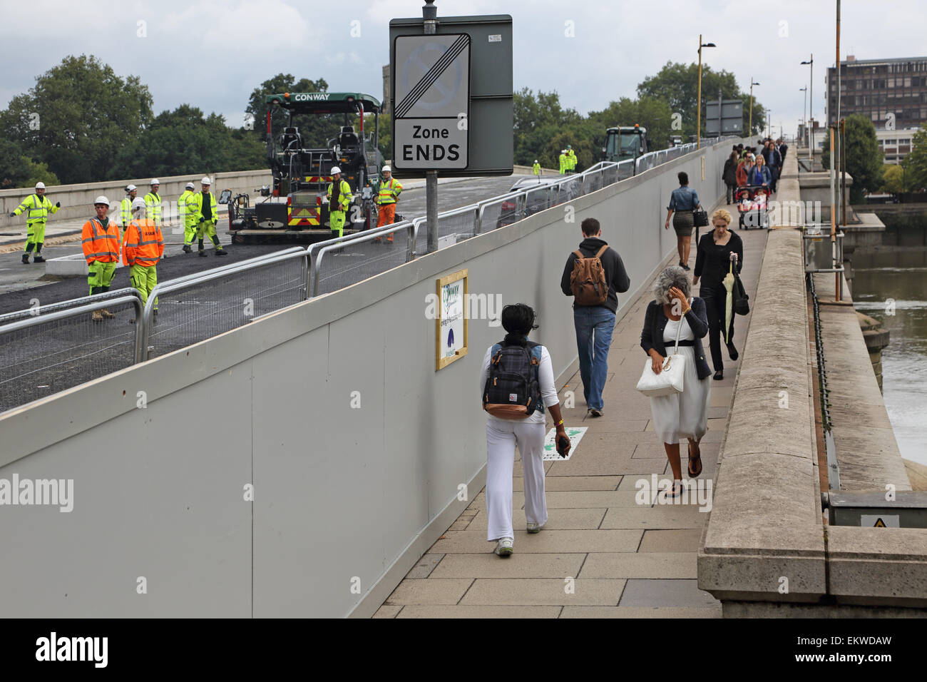 Pedestrians segregated from construction work by a temporary hoarding on Putney Bridge, west London. Bridge closed to traffic. Stock Photo
