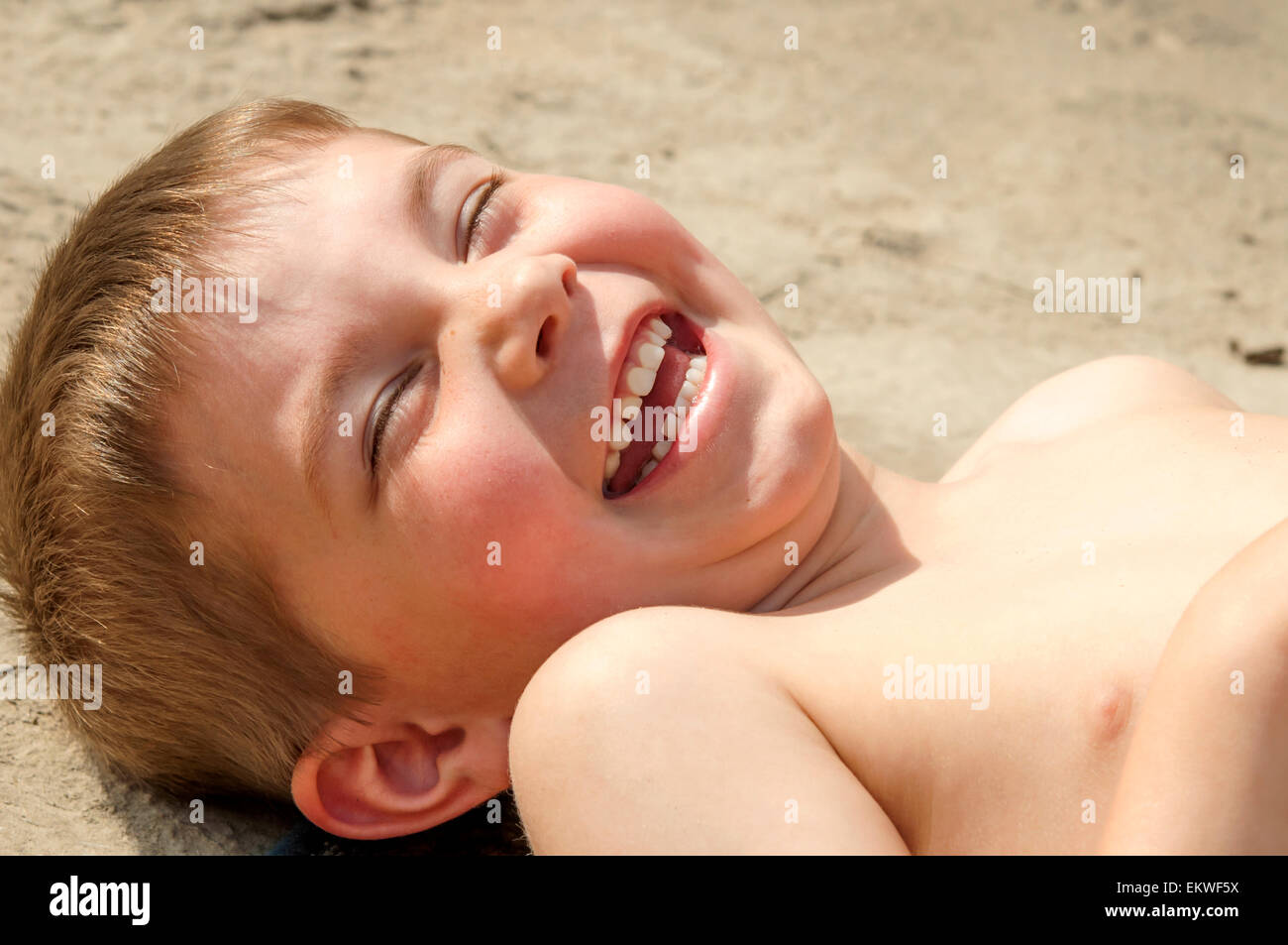 Happy boy giggling in the sand Stock Photo