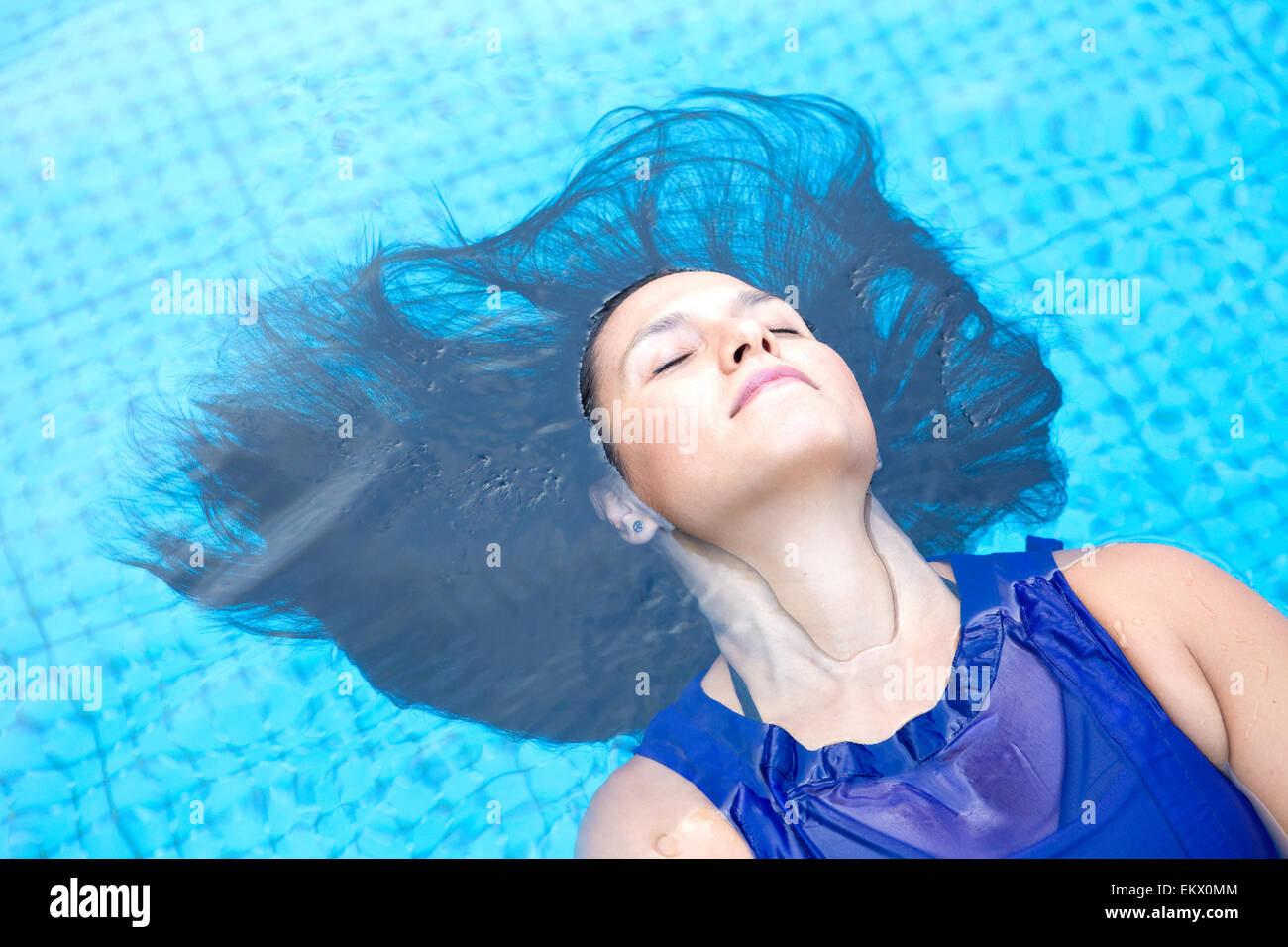 Pretty woman in a swimming pool enjoying a relaxing and peaceful moment. Stock Photo