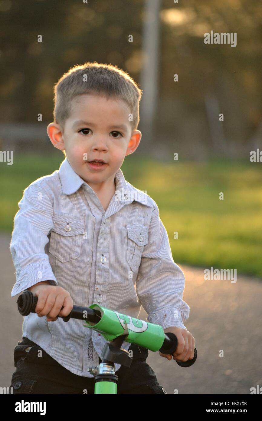 Handsome, big brown eyed 3 year old boy riding a bike. Stock Photo