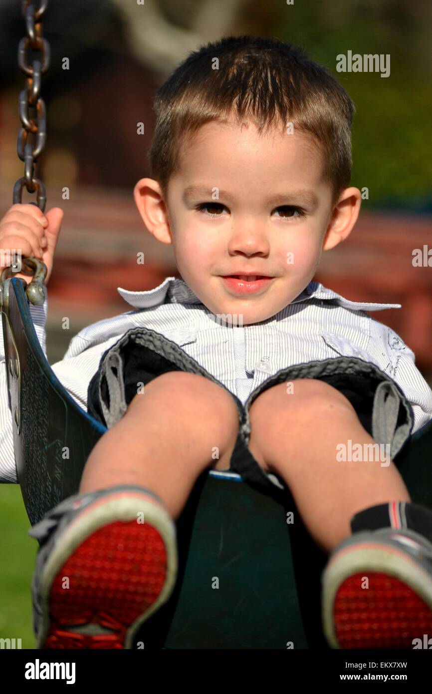 3 year old, brown eyed boy on swing. Stock Photo