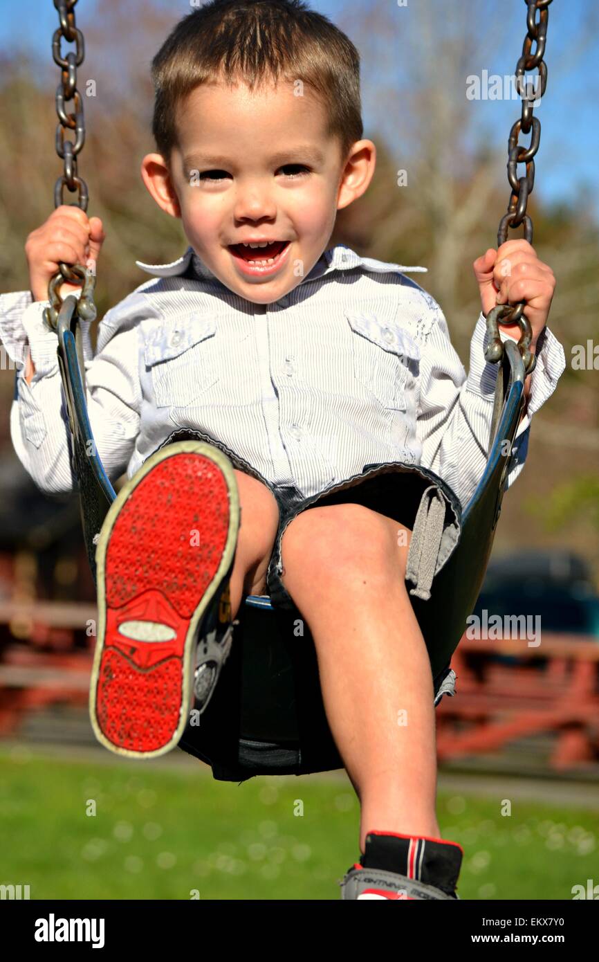 A happy, smiling, 3 year old boy smiling on a swing Stock Photo Alamy