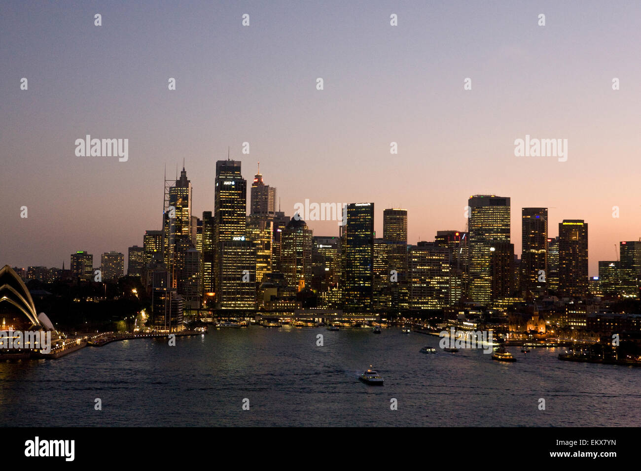 view of Circular Quay, Sydney Harbour, Australia at sunset as day turns to night and the lights come on in the city buildings Stock Photo