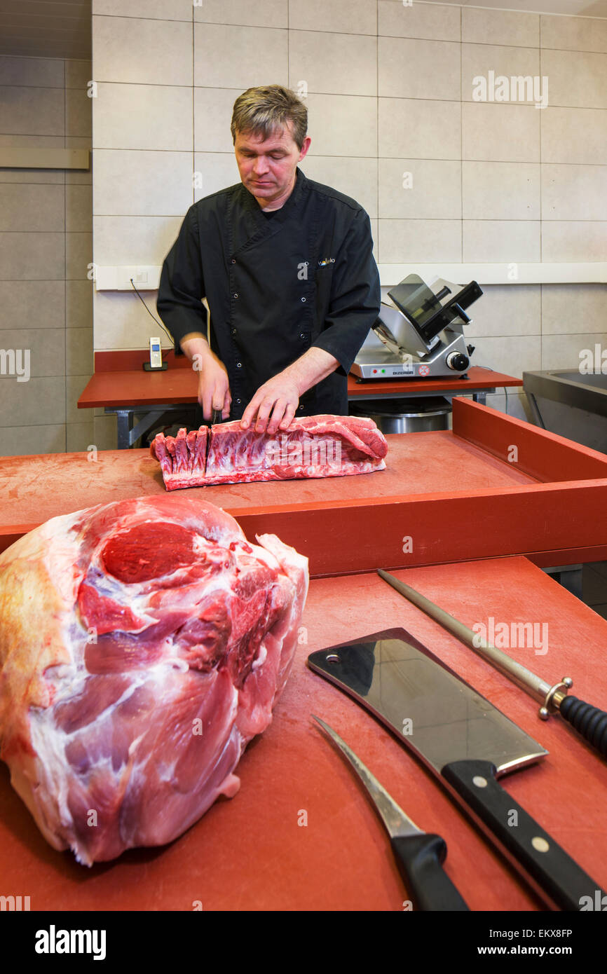Butcher / meat cutter prepares primal cuts into a variety of smaller segments for retail Stock Photo