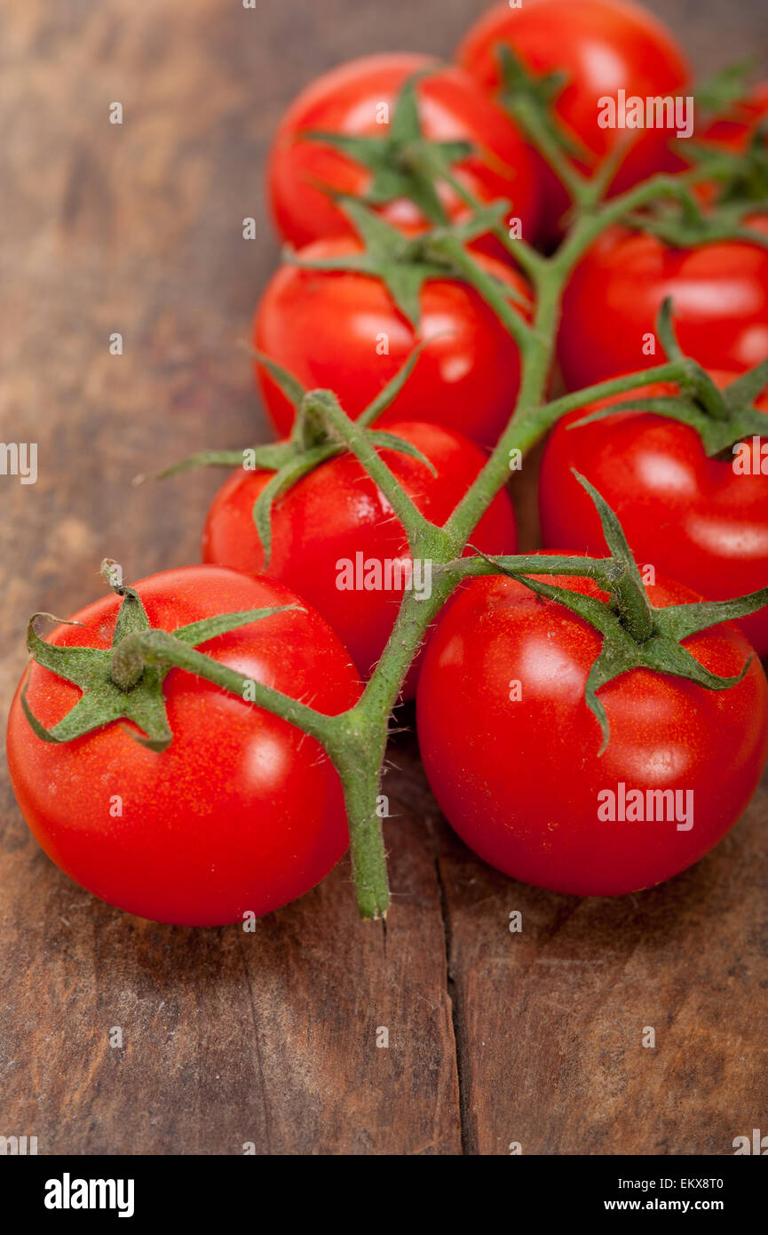 fresh cherry tomatoes on a cluster over rustic wood table Stock Photo ...