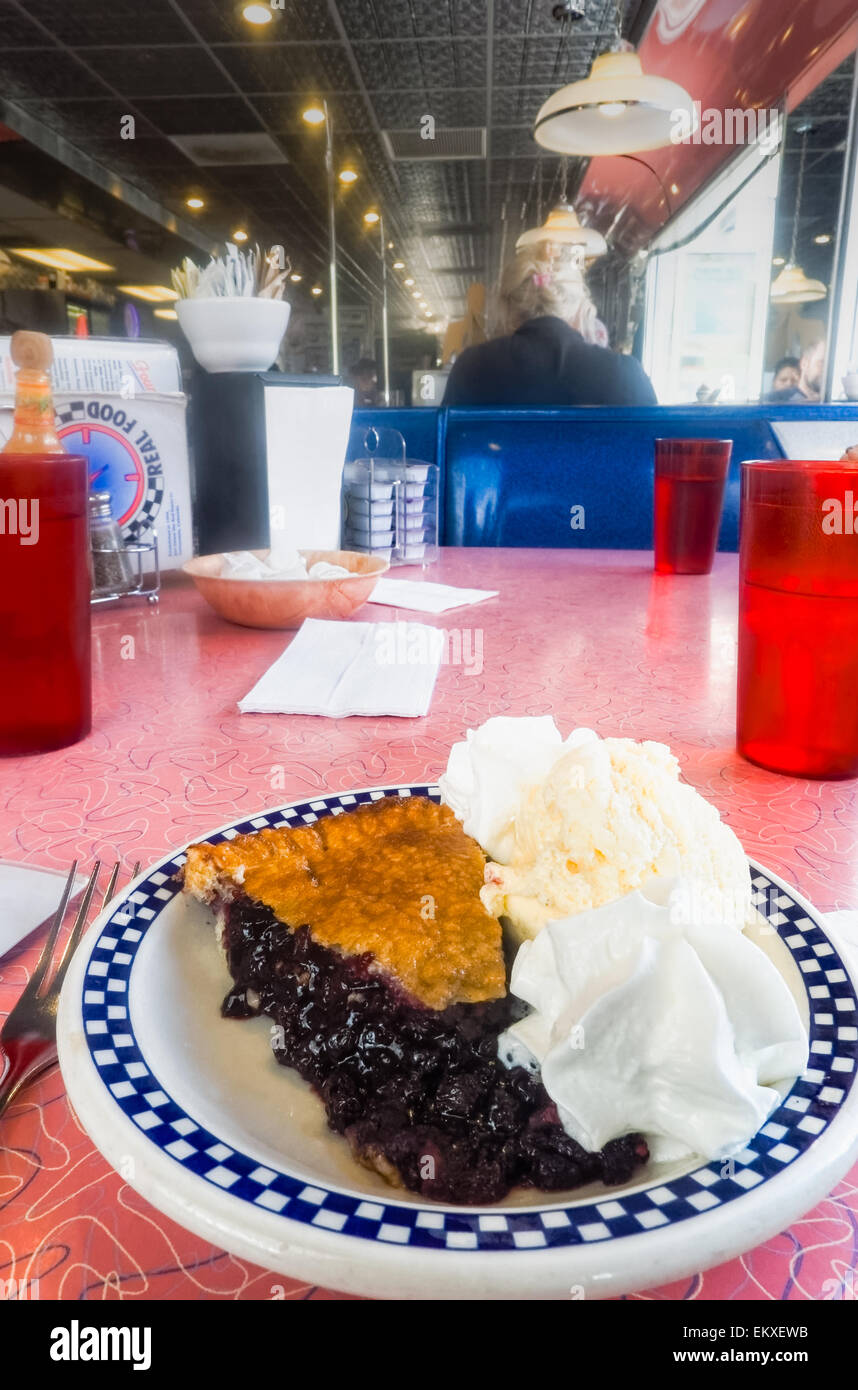 Blueberry pie a la mode with cream and ice cream in an oldfashioned
