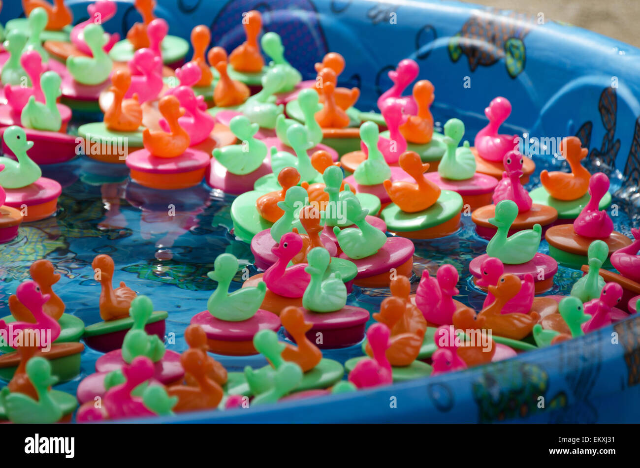 A ring-toss game at a carnival midway floats rubber ducks in a wading pool. Stock Photo