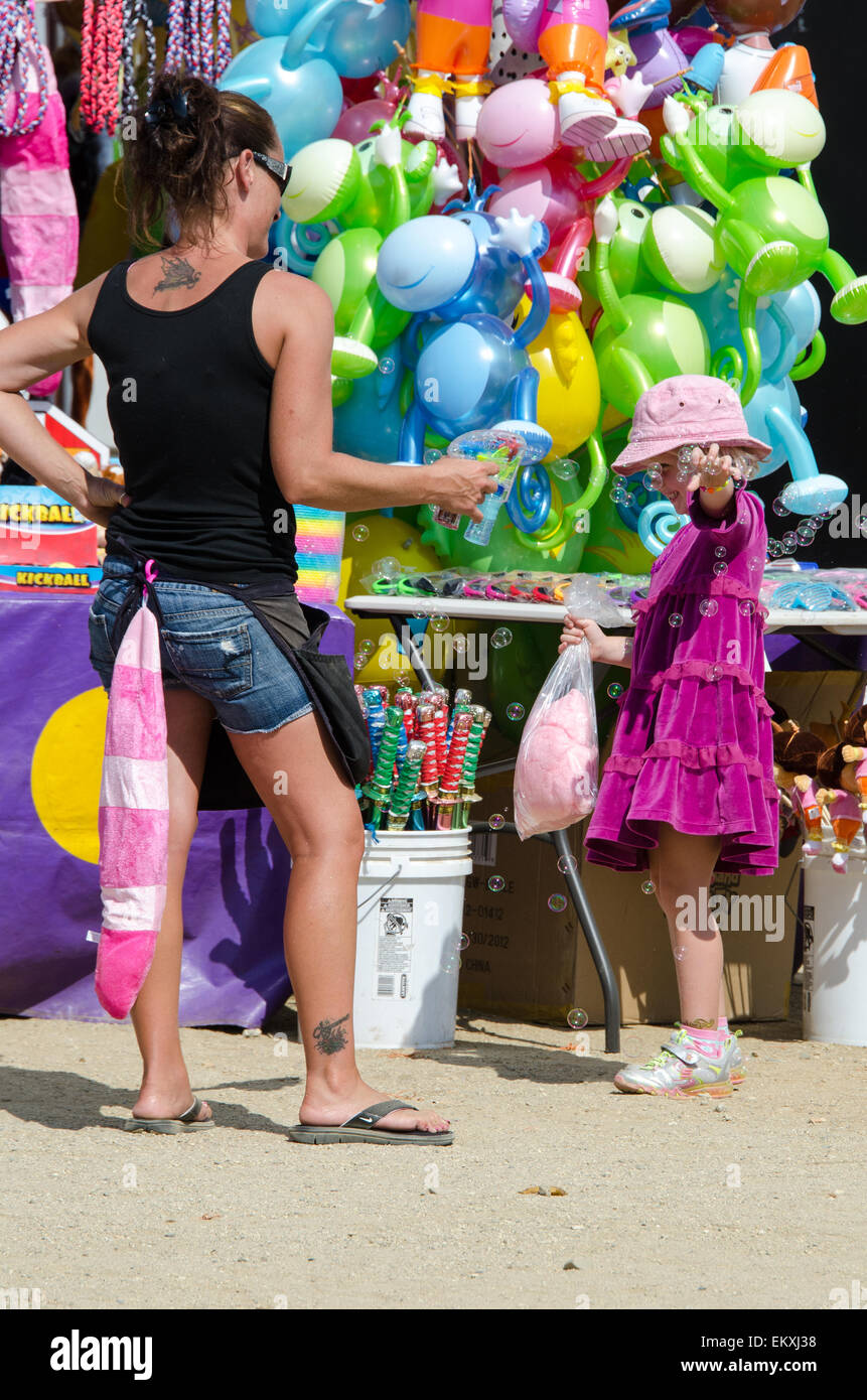 A vendor demonstrates a bubble gun to the delight of a young girl; Blue Hill Fair, Maine. Stock Photo
