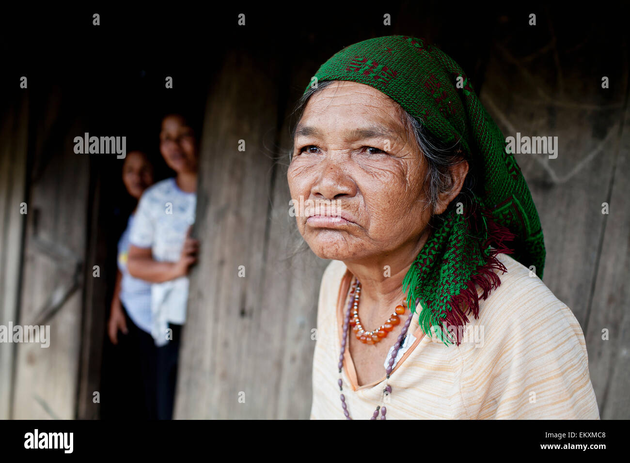 A Hill Tribe vietnamese woman sitting outside a building with people