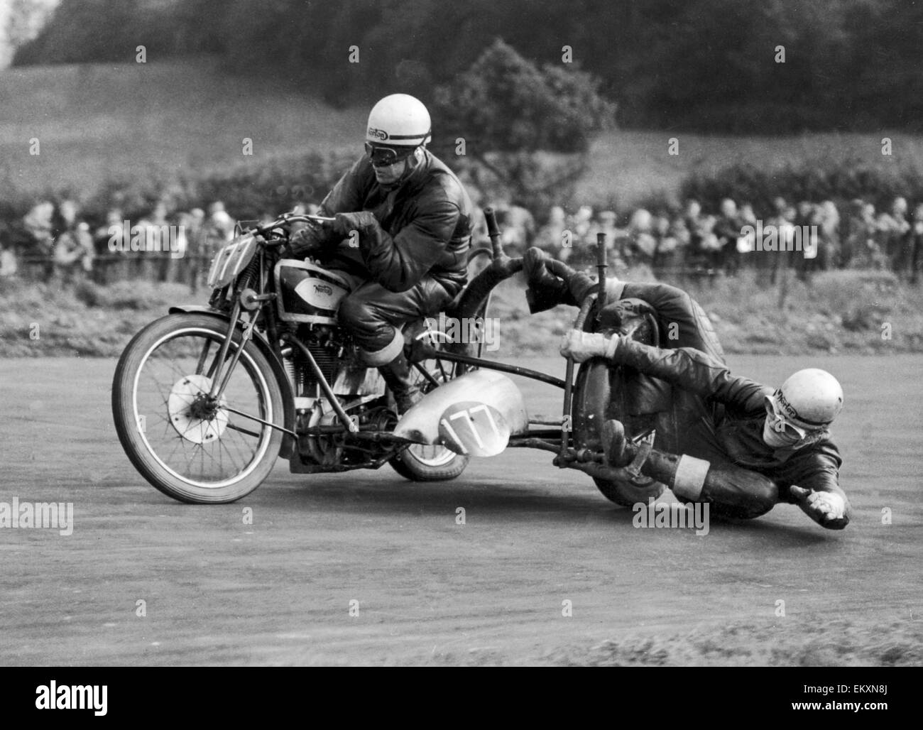 The things you have to do to keep upright! Not that this is normal motorcycle travel, of course, but taking bends at high speed, as these two are at the Brands Hatch road racemeeting, requires a lot of bias to one side or the other. And it can be mighty h Stock Photo