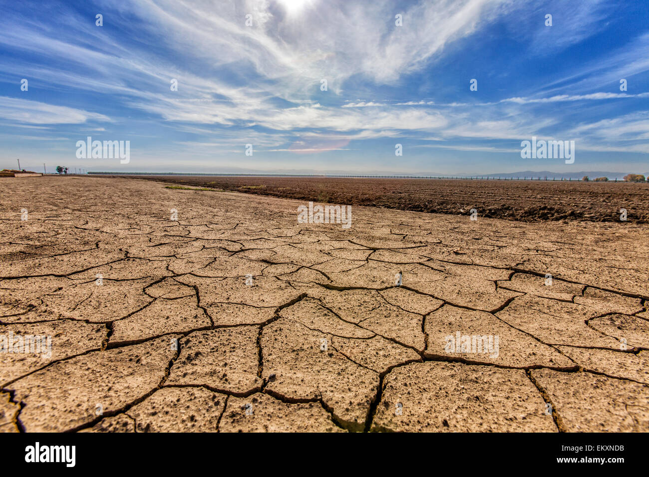 Cracked and dry earth next to fallow crop field. Fresno County, San Joachin Valley, California, USA Stock Photo