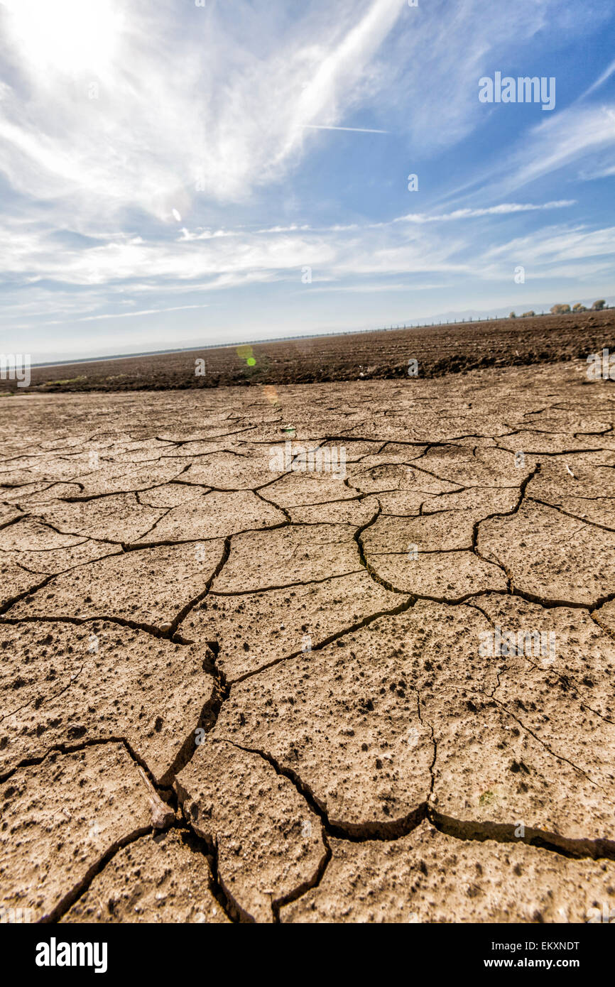 Cracked and dry earth next to fallow crop field. Fresno County, San Joaquin Valley, California, USA Stock Photo