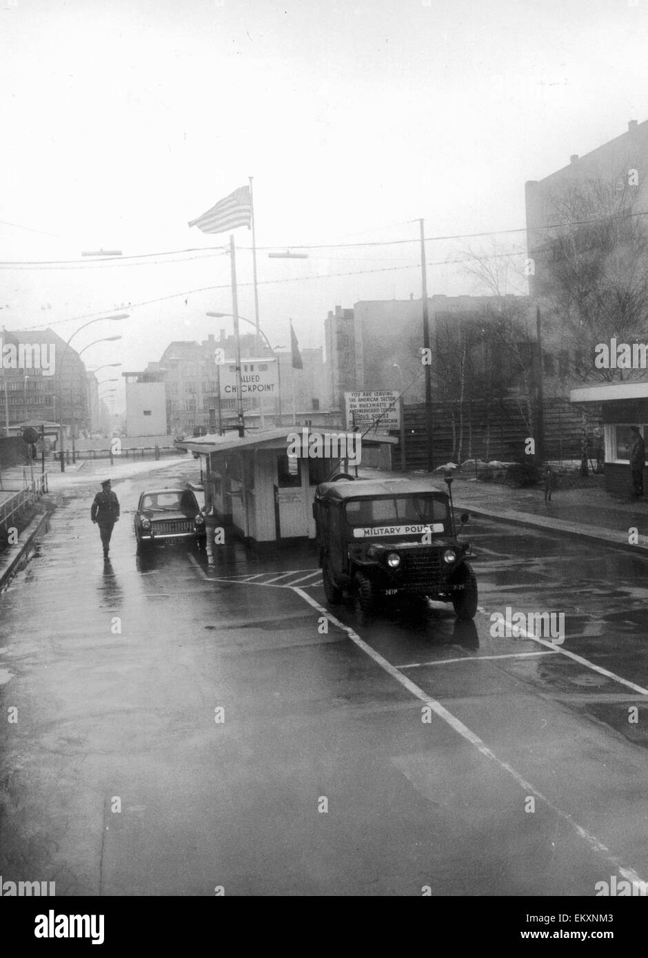 A wind swept rainy day at Checkpot Charlie on Berlin Friedrich strasse. In June 1953 during the workersÍ revolt in East Germany, American and Soviet tanks stood opposite each other in Friedrich Strasse, creating a credible threat of force at the Allies se Stock Photo