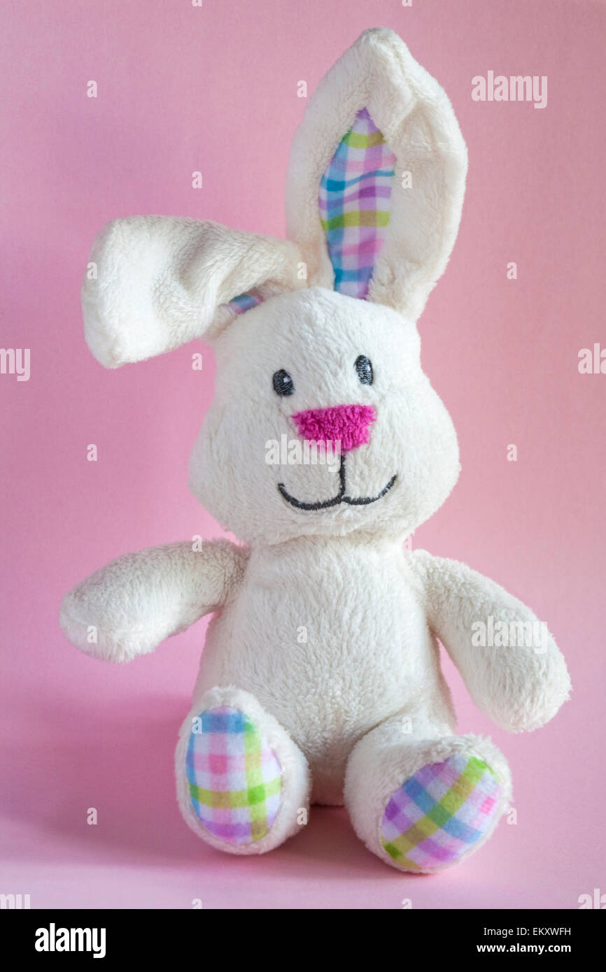 Easter bunny rabbit soft cuddly toy sitting against pink background Stock Photo