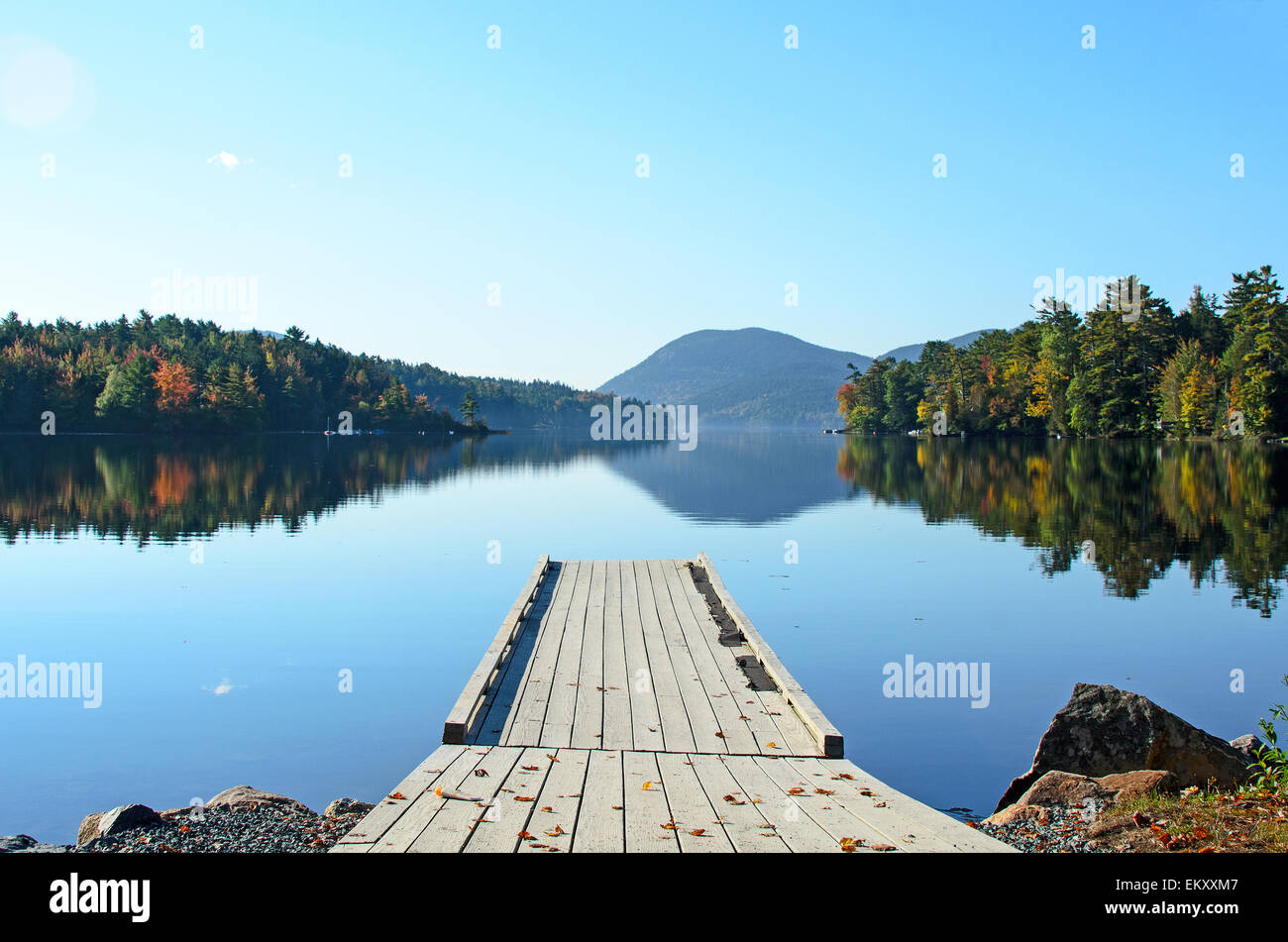 Looking over the dock at fall foliage reflected in the still waters of Long Pond on Mount Desert Island, Maine. Stock Photo