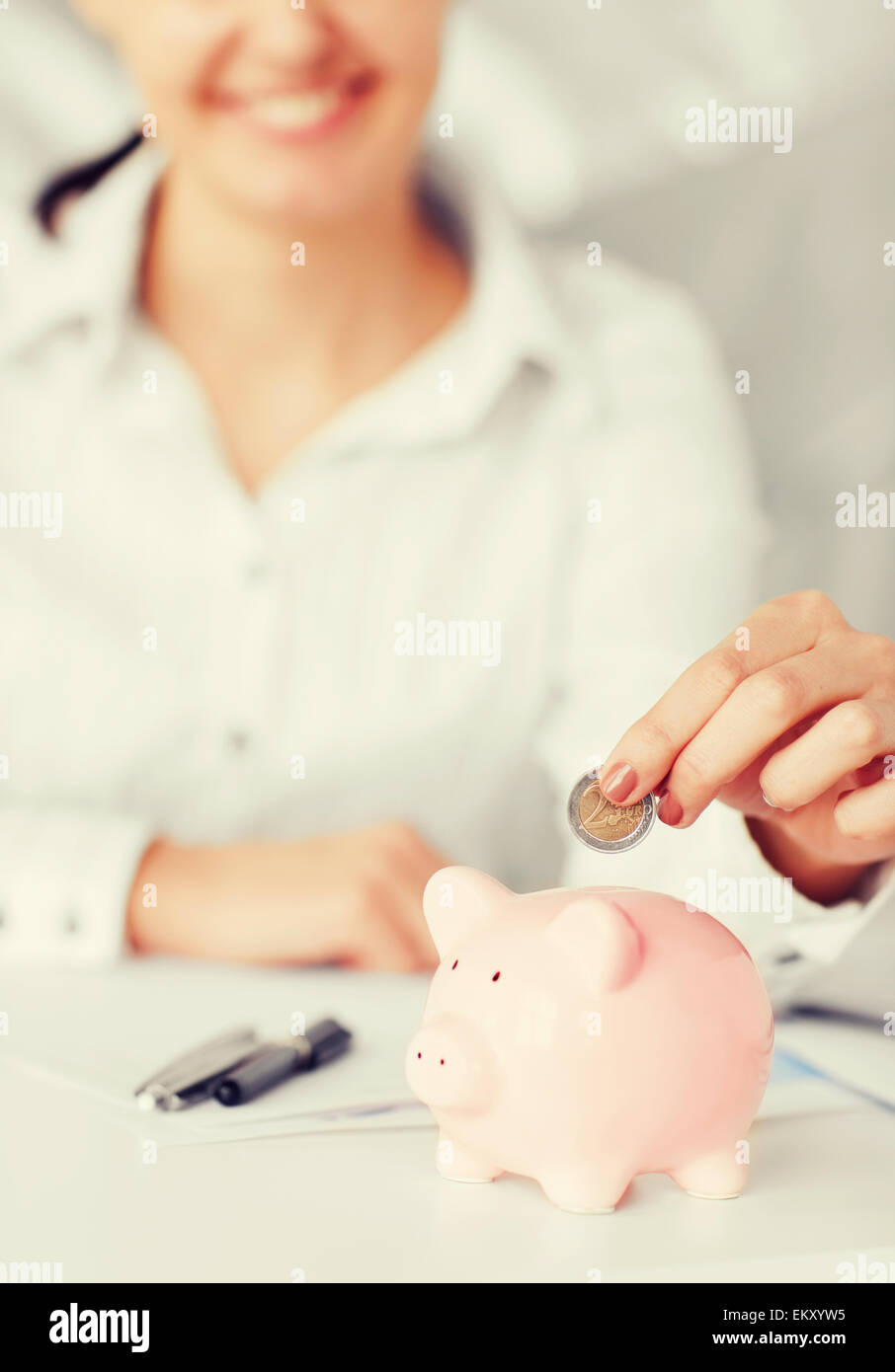 Happy businesswoman putting an euro coin into a piggy bank isolated on ...