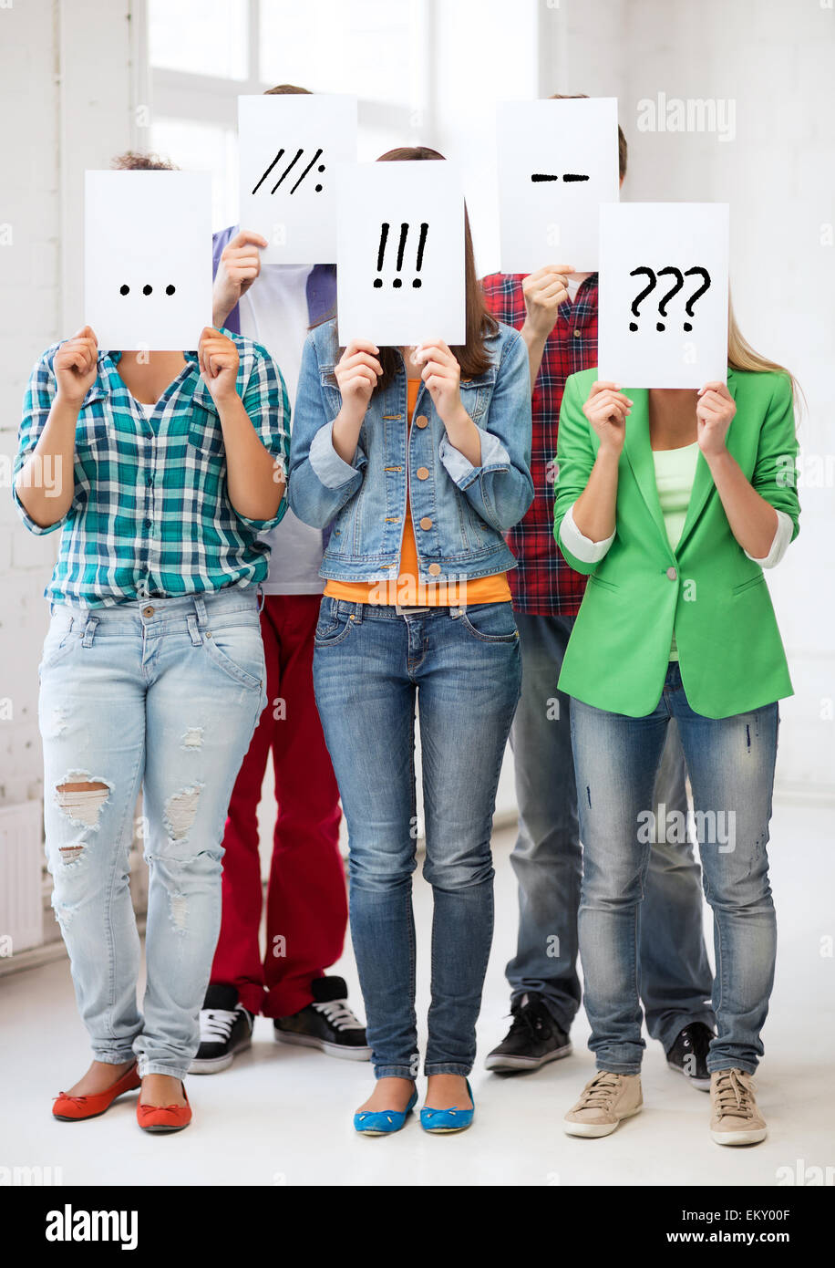 friends or students covering faces with papers Stock Photo