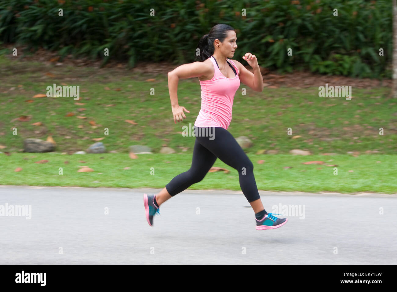 Young hispanic woman doing sprinting exercise in park Stock Photo
