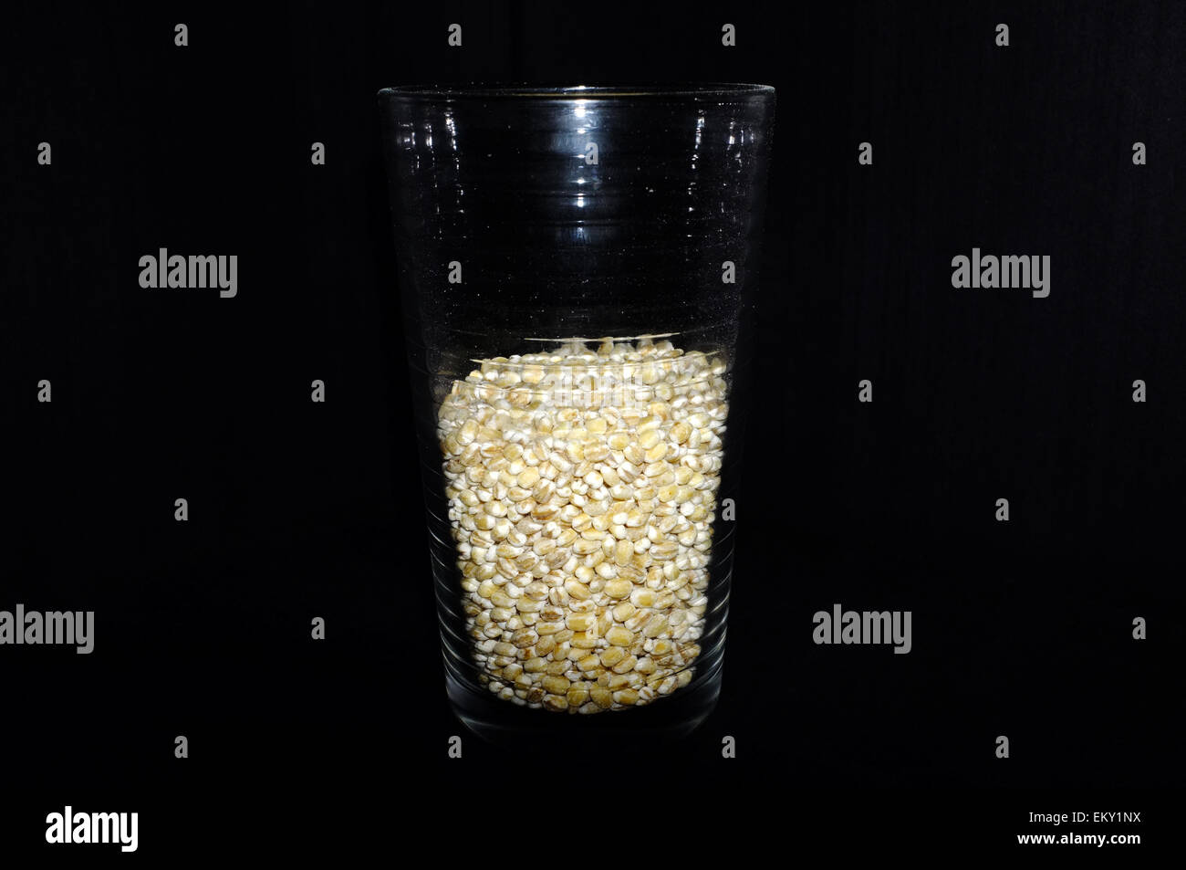 A glass half full/half empty of  photographed against a black background. Stock Photo