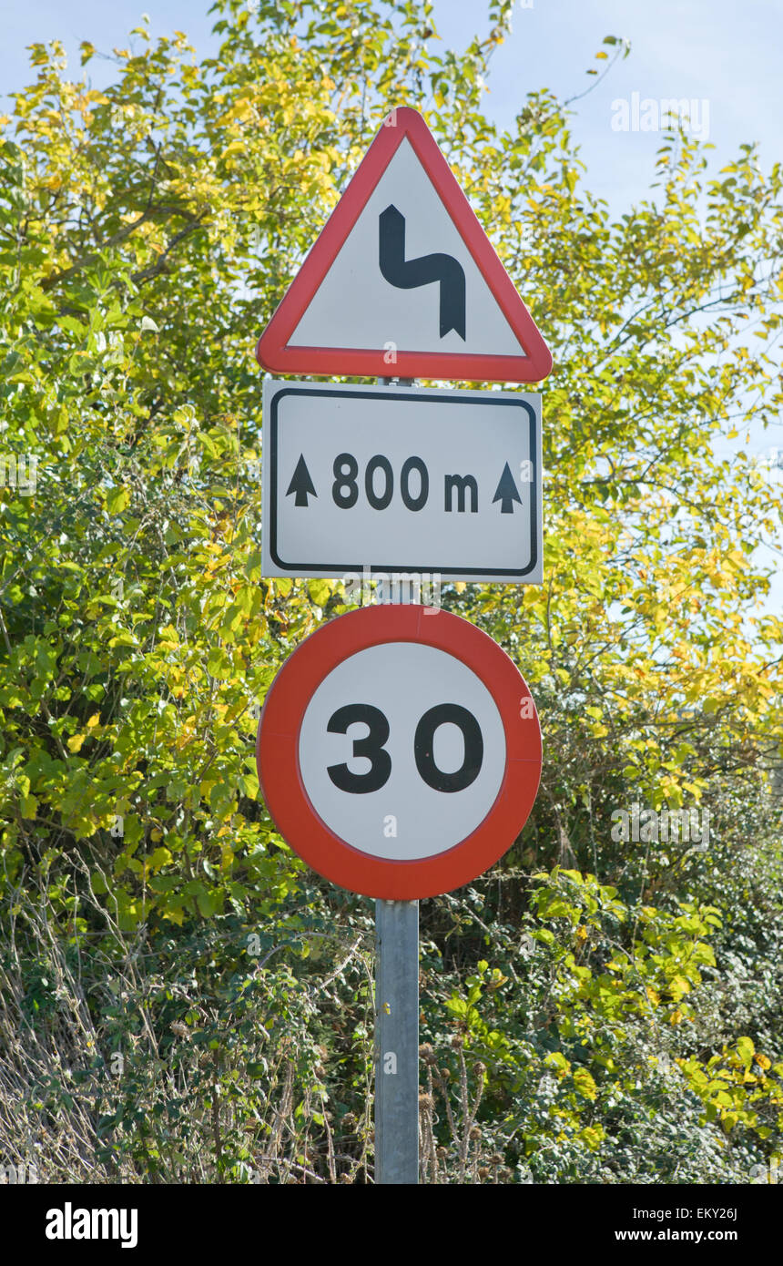 Warning sign for sharp curves ahead in a forest pass, Caceres, Spain Stock Photo