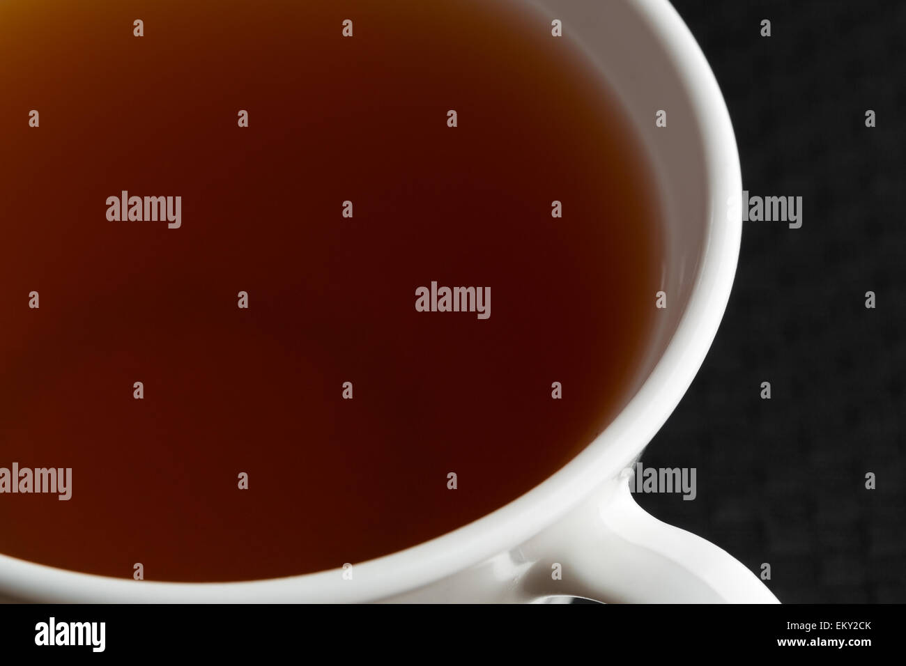 A very close view of a cup of passion fruit green tea on a black tablecloth. Stock Photo