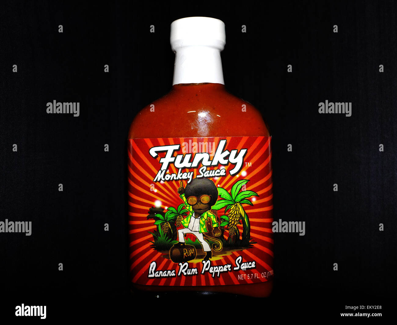 A bottle of hot chilli sauce photographed against a black background