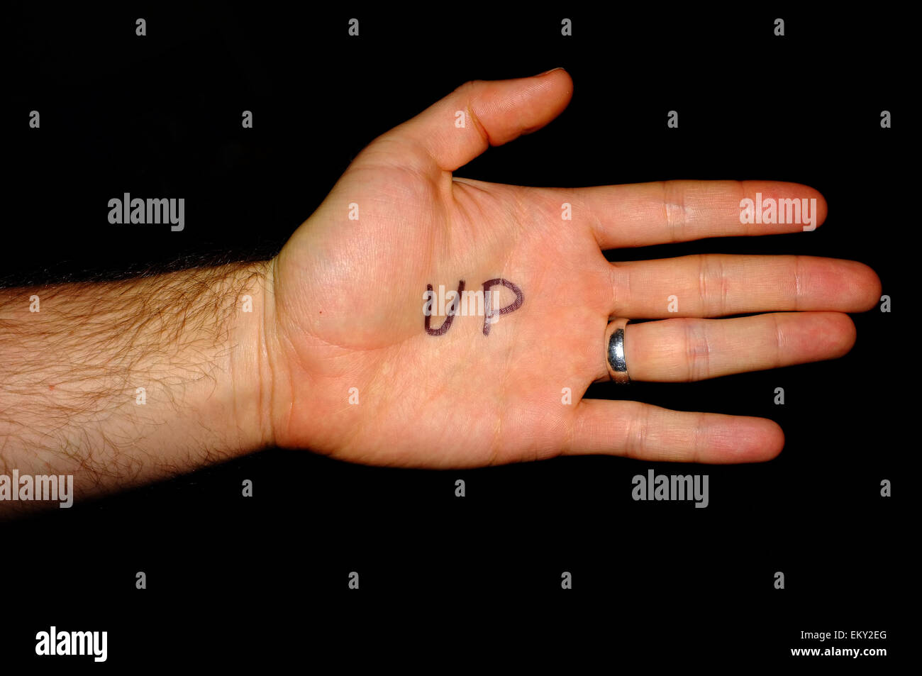Up written on a white man's hand photographed against a black background. Stock Photo