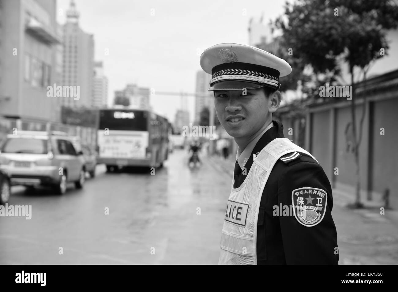 A Young Policeman Standing On The Side Of A Street; Ruili Yunnan China Stock Photo