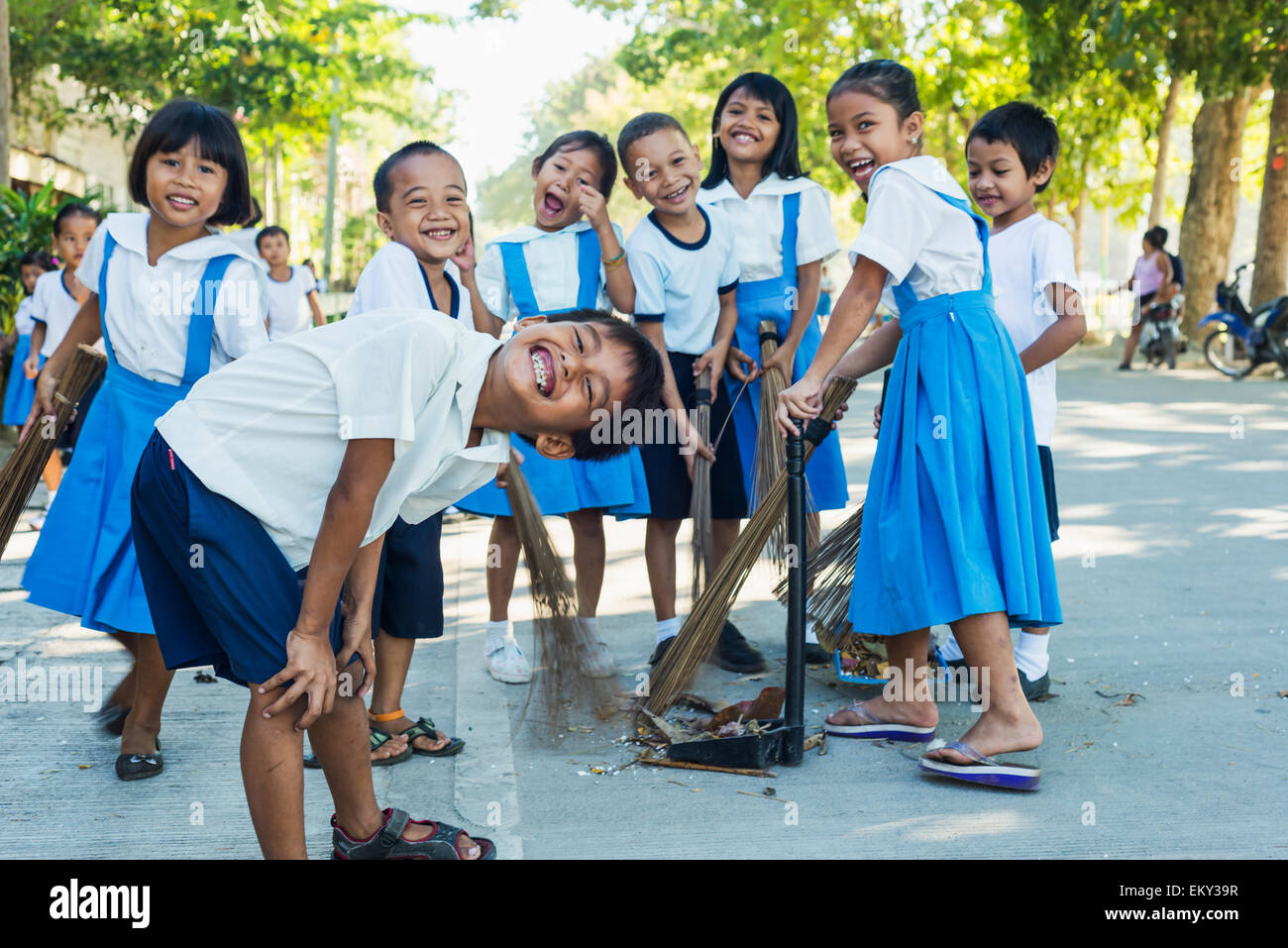 Young school children playing and cleaning the street of their school; Panglao town, Panglao island, Bohol, Philippines Stock Photo
