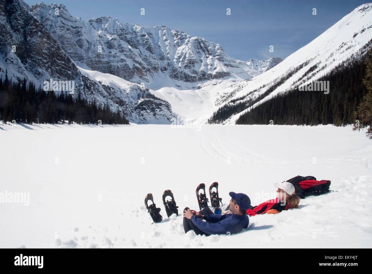 Couple On Snowshoes Sitting By Taylor Lake, Banff National Park; Banff