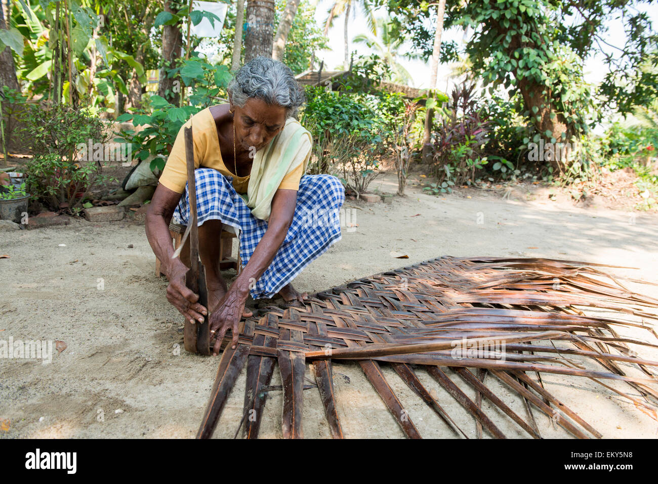 An elderly Indian woman weaving a mat as part of an authentic village