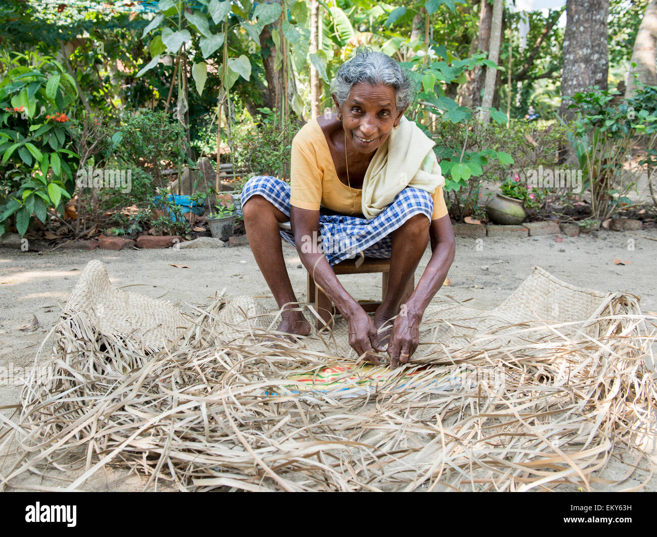 An elderly Indian woman weaving a mat as part of an authentic village