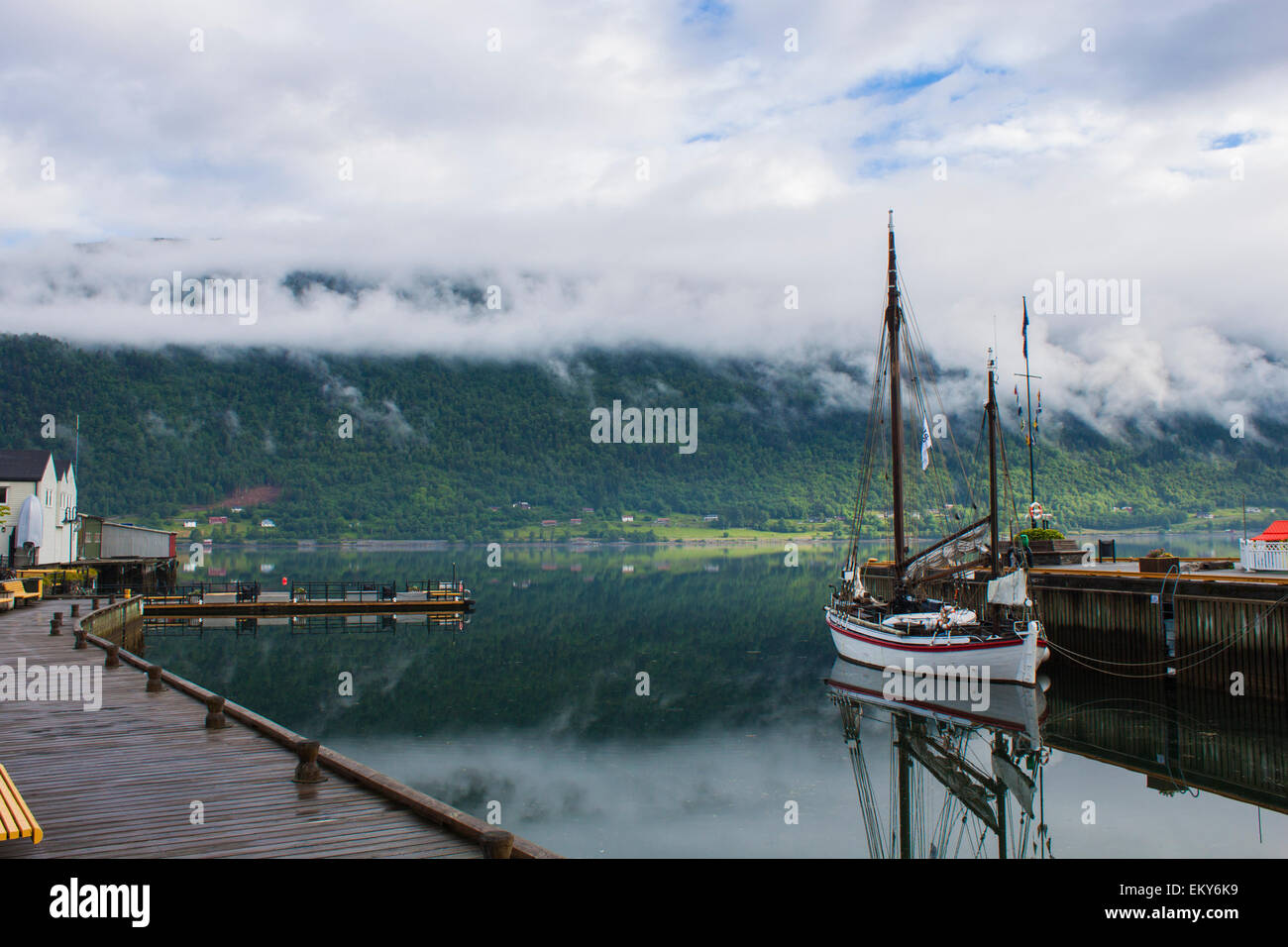 Calm morning at the habour in Åndalsnes on the Romsdalsfjord in Norway with clouds rolling over the mountains Stock Photo