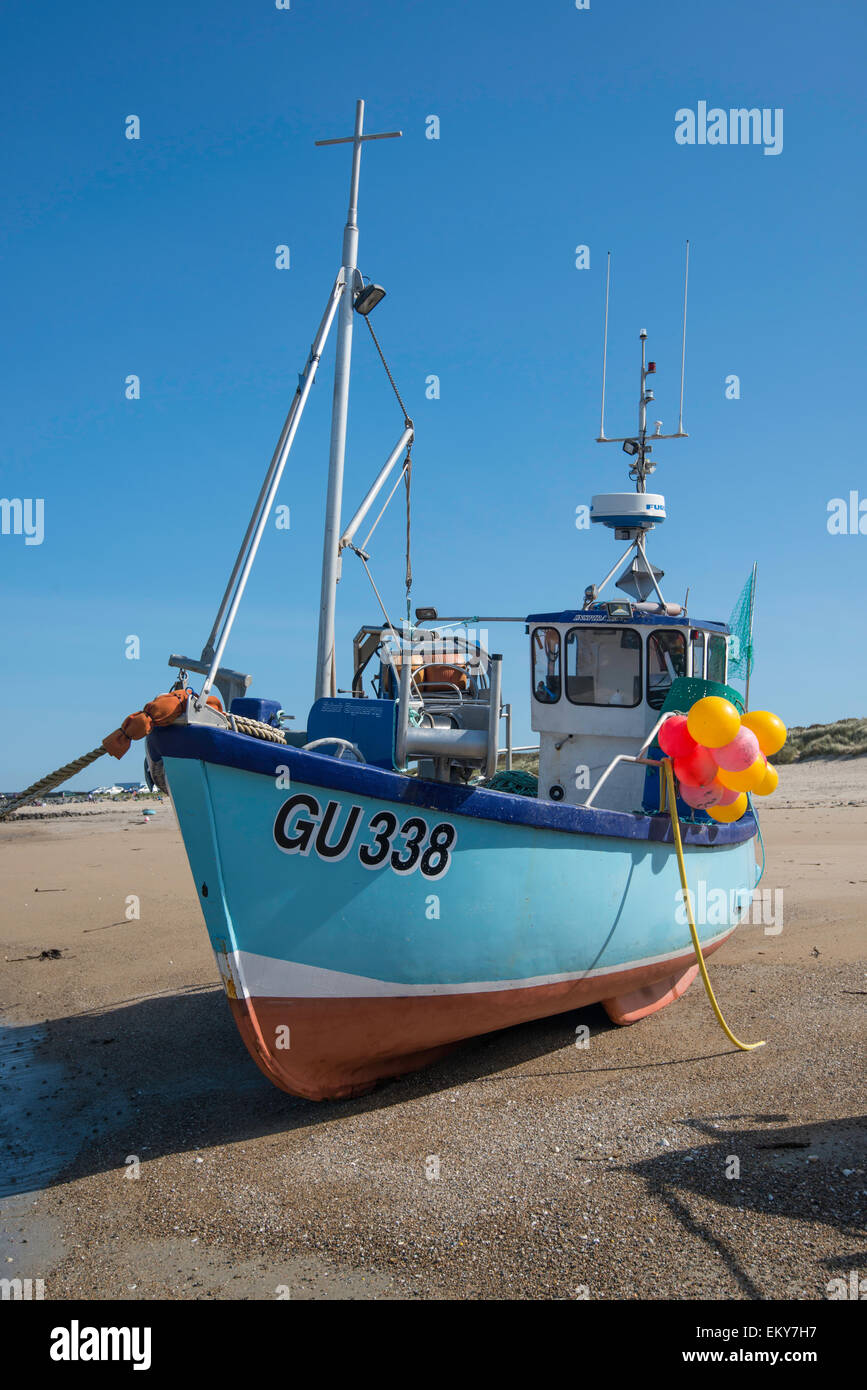 Fishing boat dried out on sandy beach at low tide. Stock Photo