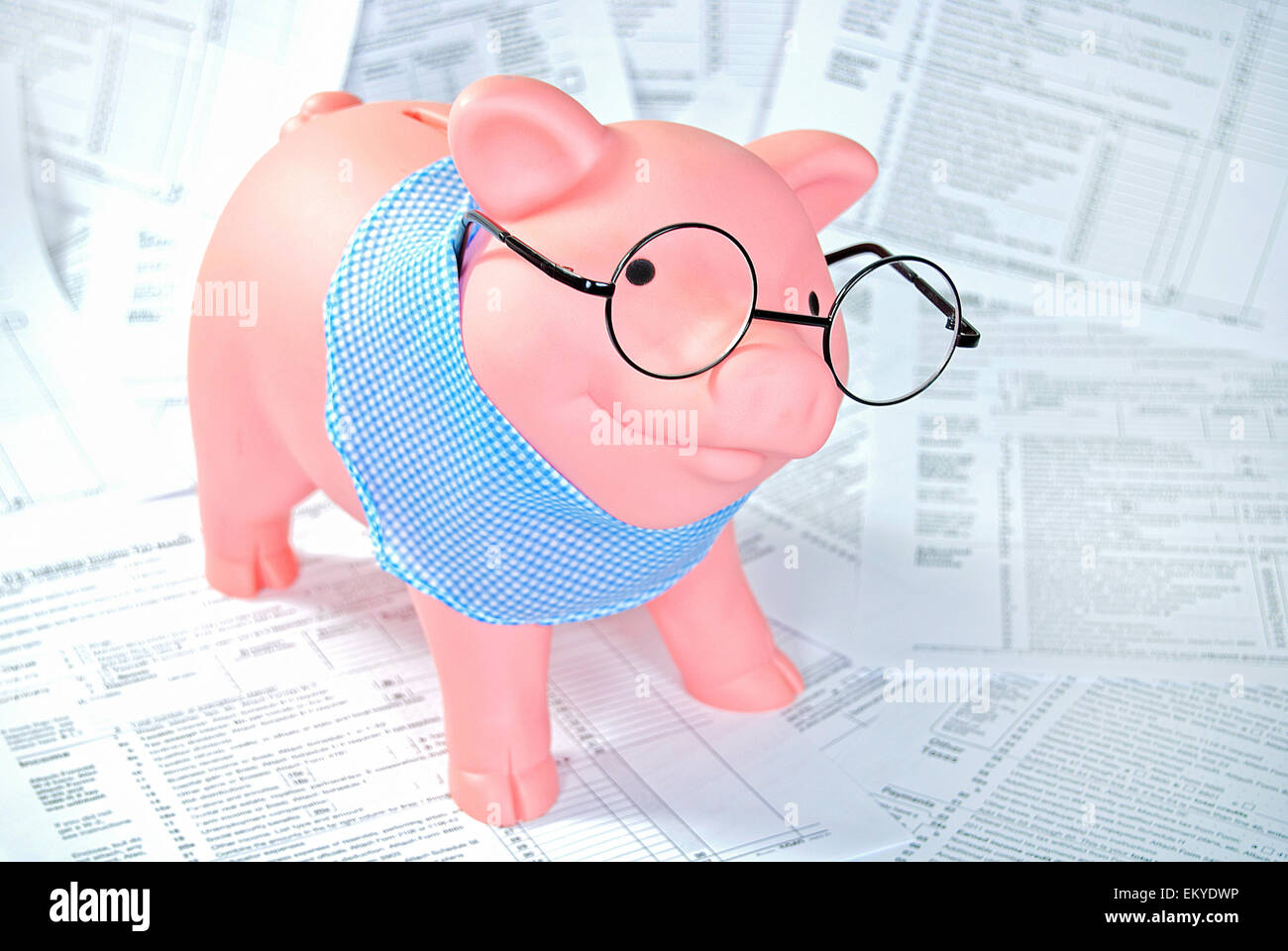 Piggy bank with glasses and gingham scarf on income tax forms. Stock Photo