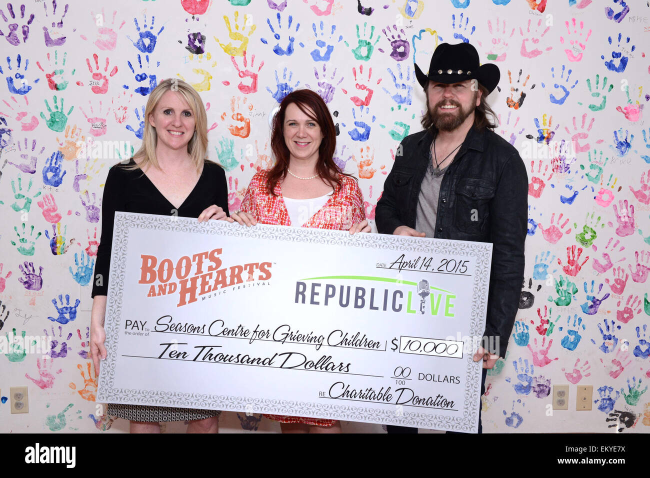 Barrie, Ontario, Canada. 14th April 2015. Canadian country music singer Jason McCoy at the presentation of $10,000 donation check from Republic Live on behalf of Boots and Hearts to the Seasons Centre for Grieving Children. In picture, Marcy Baldry of Seasons Centre for Grieving Children, Laura Kennedy or Republic Live, and Jason McCoy. © EXImages/Alamy Live News Stock Photo