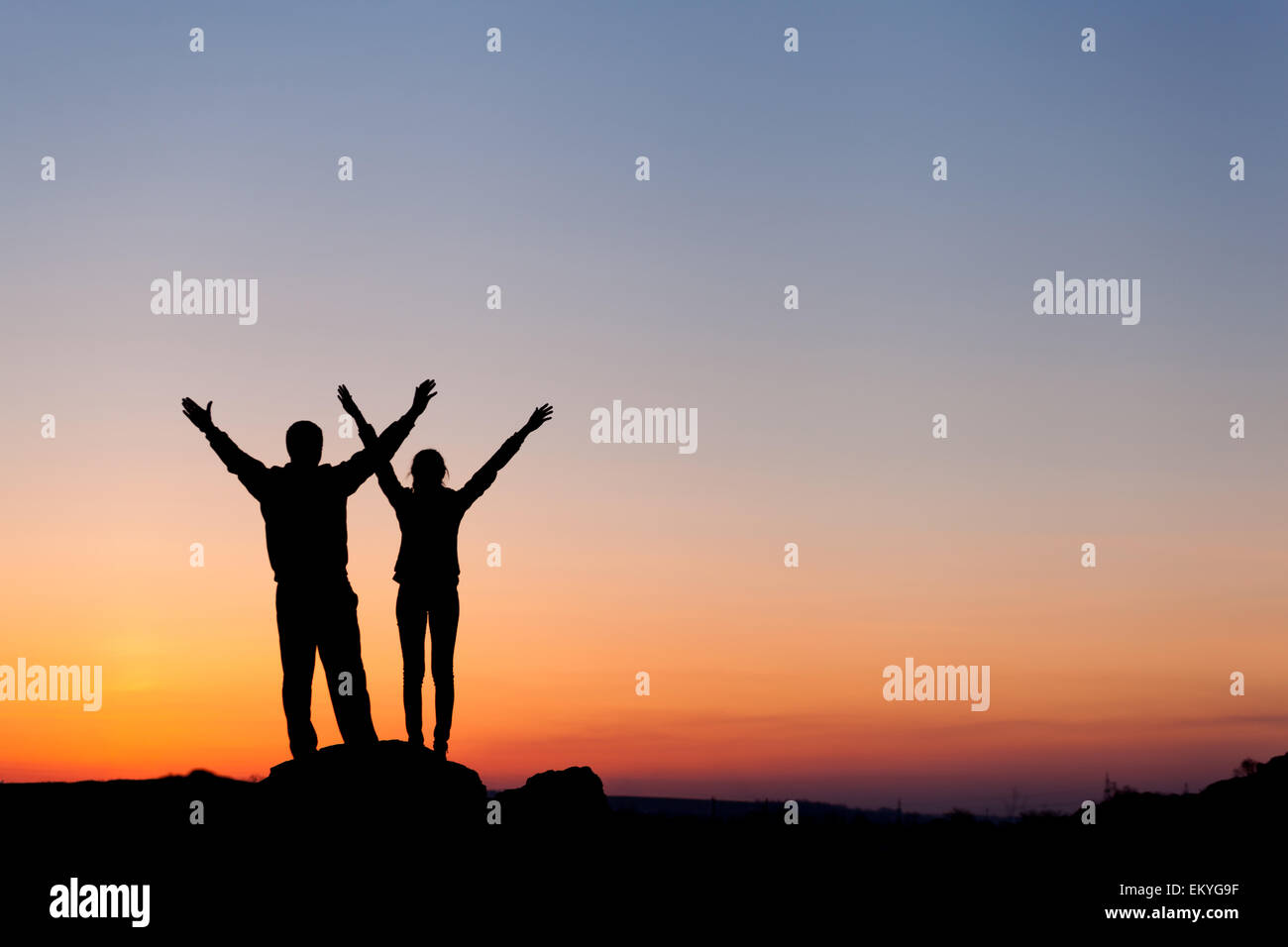 Silhouette of happiness family with arms raised up against beautiful colorful sky. Summer Sunset. Landscape Stock Photo