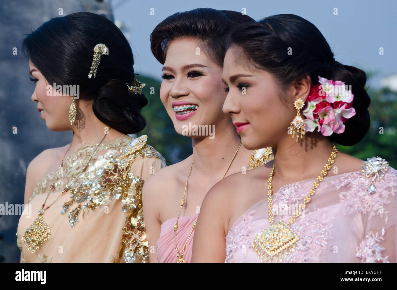 A Thai bride and her bridesmaids enjoy a wedding ceremony in Thailand. Bride shows beautiful teeth and braces. Stock Photo