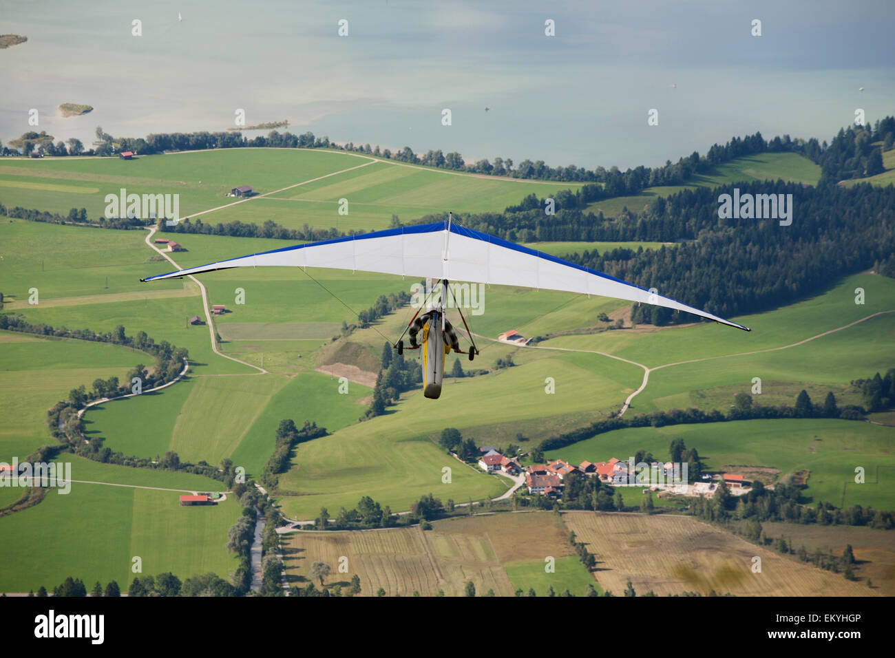 Hang Glider Flying Over Fields And Lake Below; Schwangau, Germany Stock