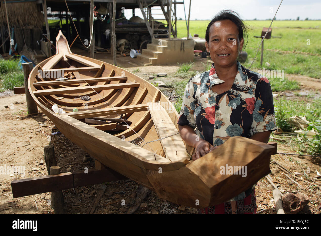 Wife of a master boat builder standing beside a boat under construction; Prek Chhdor Village, Battambang Province, Cambodia Stock Photo