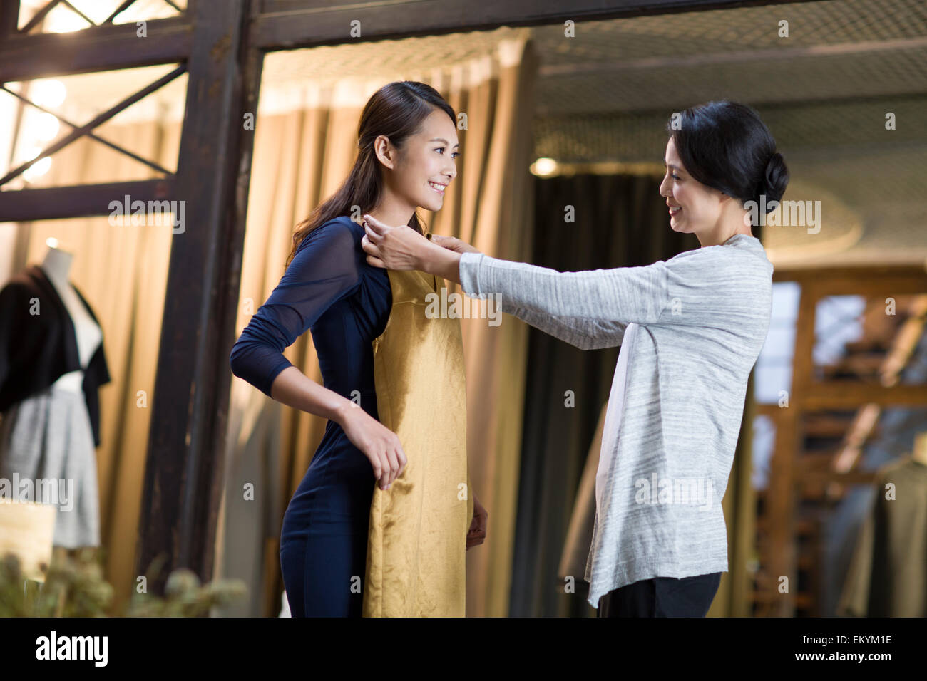 Clothing store owner helping customer with choosing dress Stock Photo