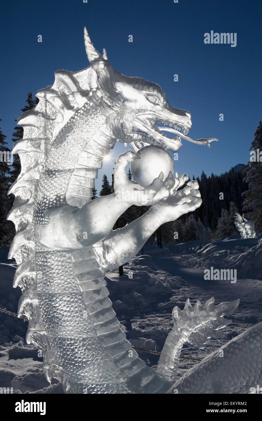 A Backlit Ice Sculpture Of A Dragon Holding A Sphere With Blue Sky And ...