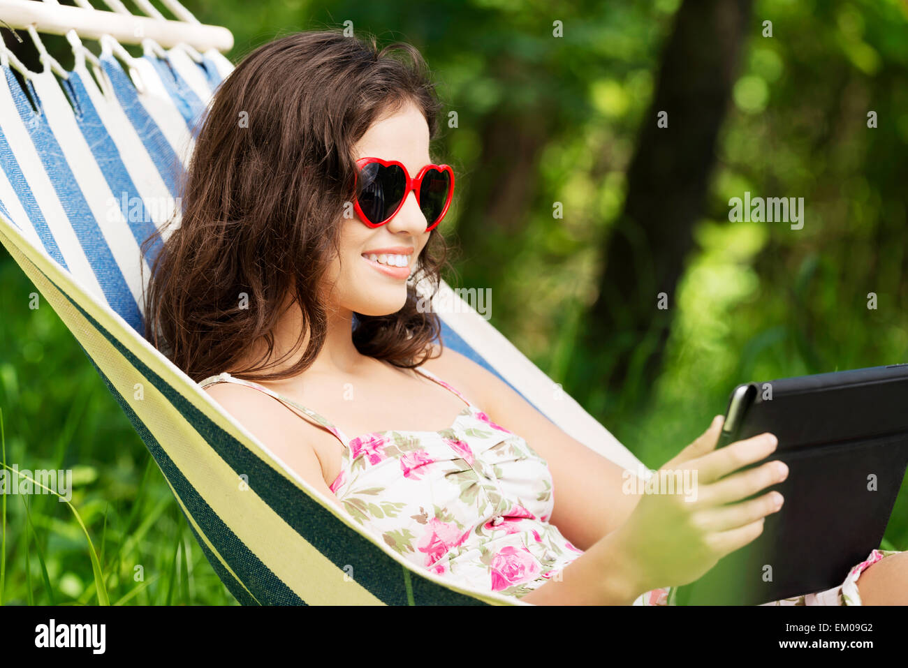 Young woman lying in a hammock in garden with E-Book Stock Photo - Alamy