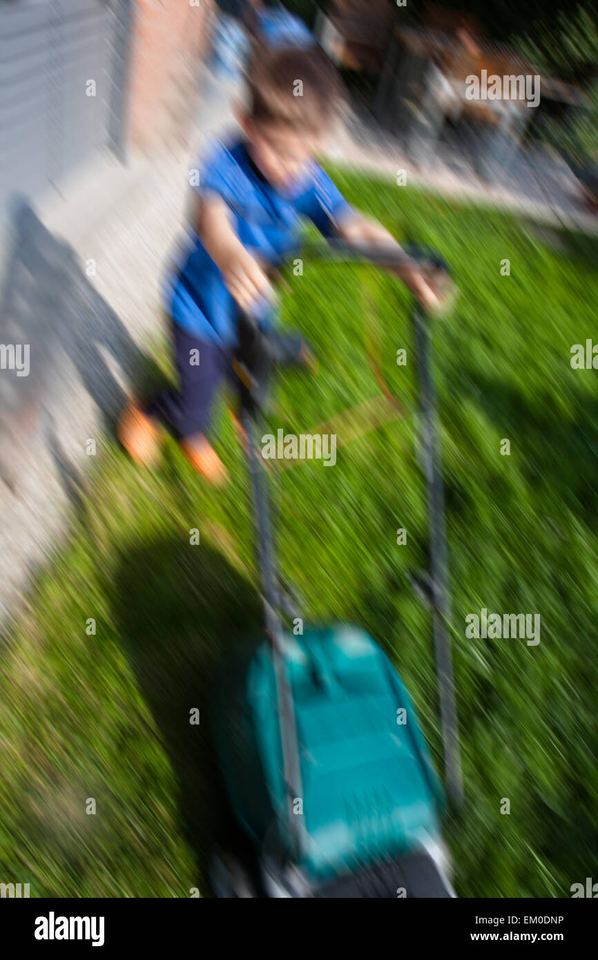 child who cuts the lawn with electric mower Stock Photo