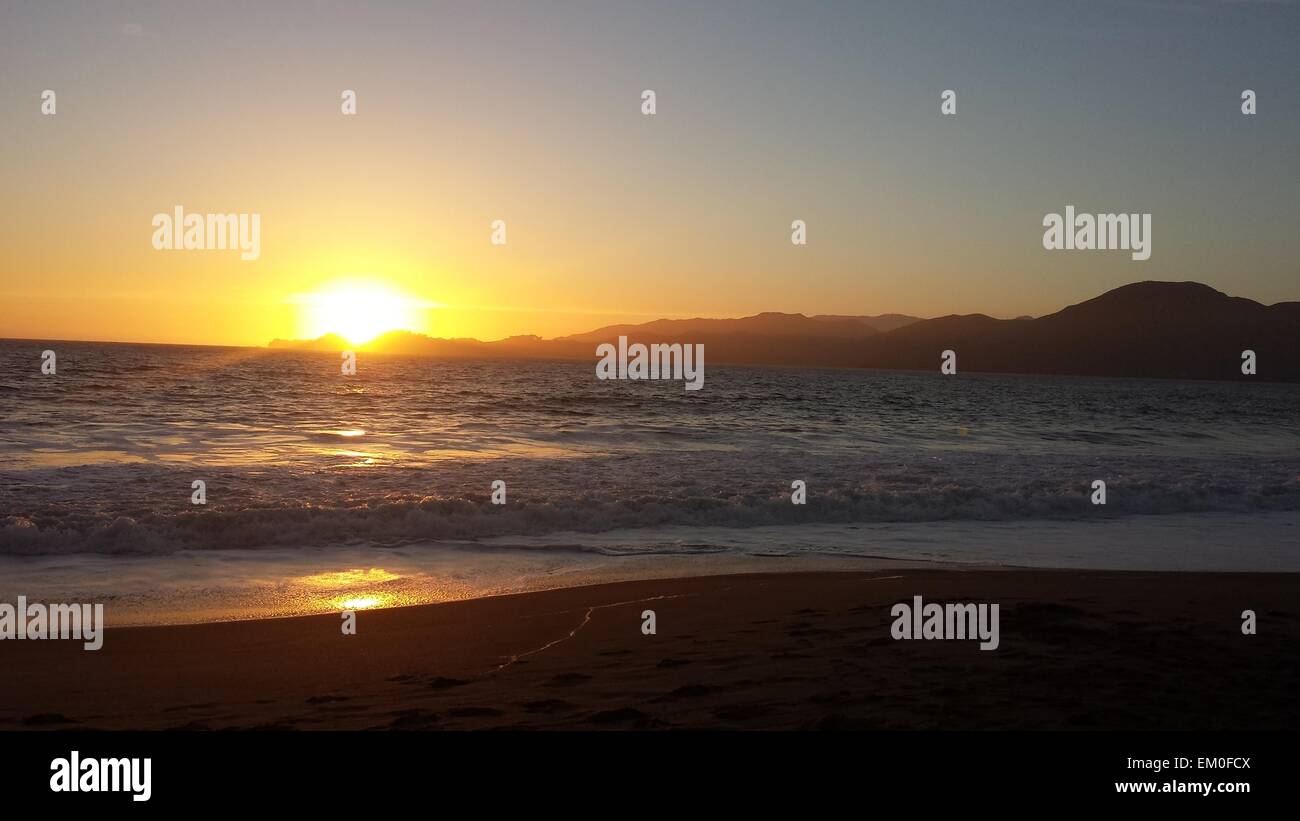 Vivid sun setting over the ocean Stock Photo - Alamy