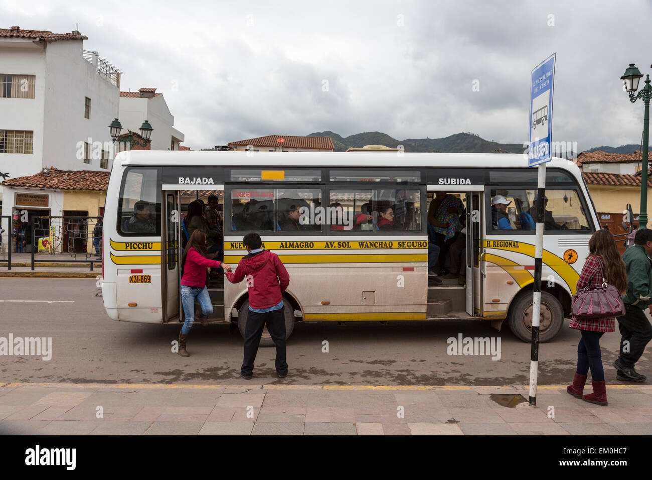 Peru, Cusco.  Local Transport.  Fare-collector Collects Payment from Passenger as she Gets Off the Bus. Stock Photo